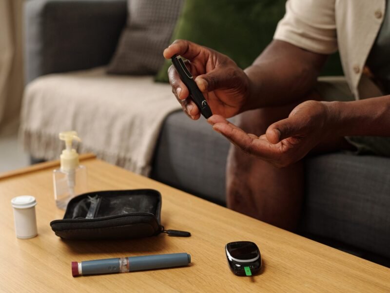 Person using a lancet pen to prick their finger for a blood glucose test at home.